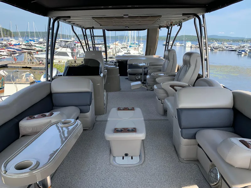 Slide: The Image of 2013 Premier 310 Boundary Waters Sky Dek pontoon boat interior with luxurious seating and marina view. - 7