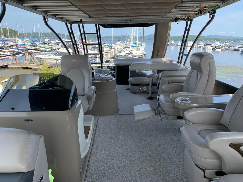 Slide: The Image of 2013 Premier 310 Boundary Waters Sky Dek pontoon boat interior with luxurious seating and marina view. - 8