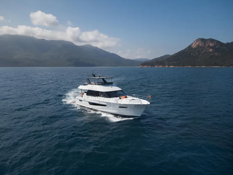 Slide: The Image of 2024 CL Yachts CLB65 cruising on open water with scenic mountain backdrop. - 3
