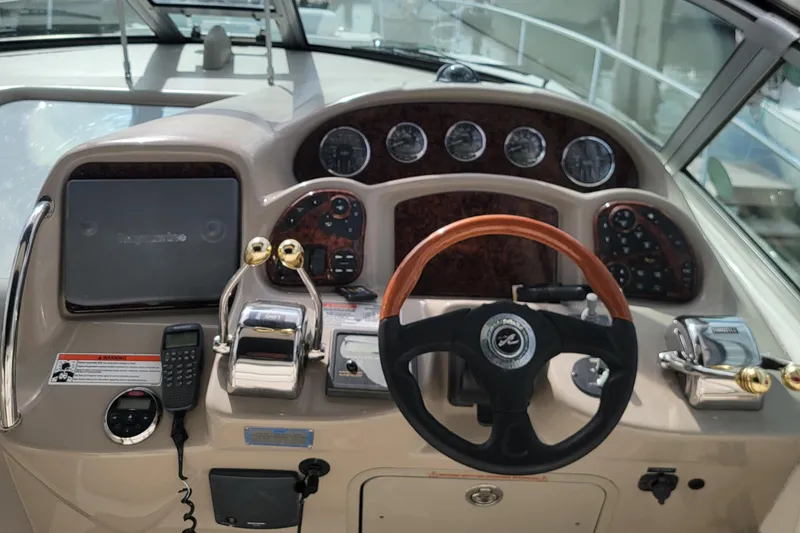 Slide: The Image of 2006 Sea Ray 320 Sundancer helm with gauges, steering wheel, and controls. - 11
