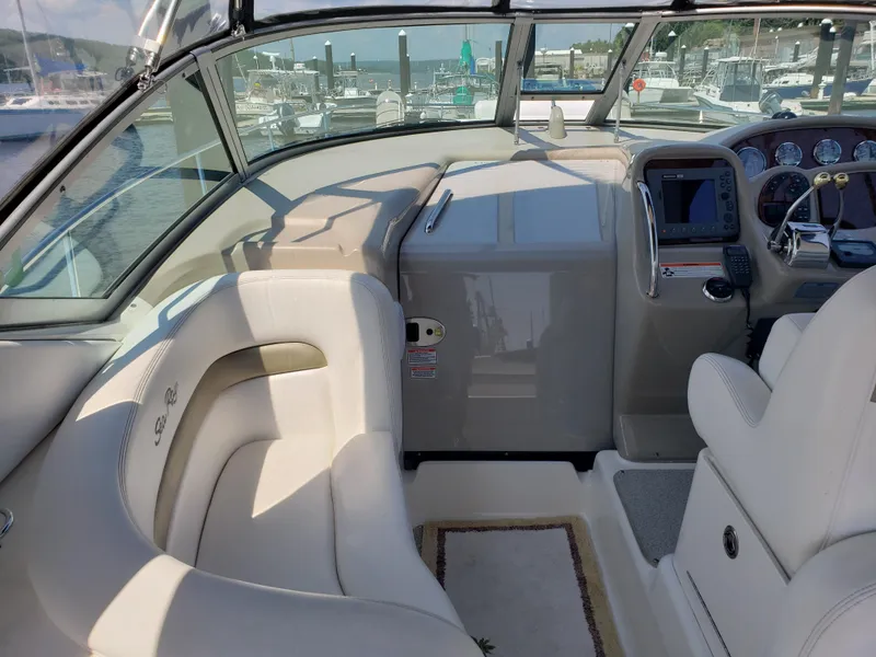 Slide: The Image of 2006 Sea Ray 320 Sundancer cockpit with helm, white seating, and marina view. - 17