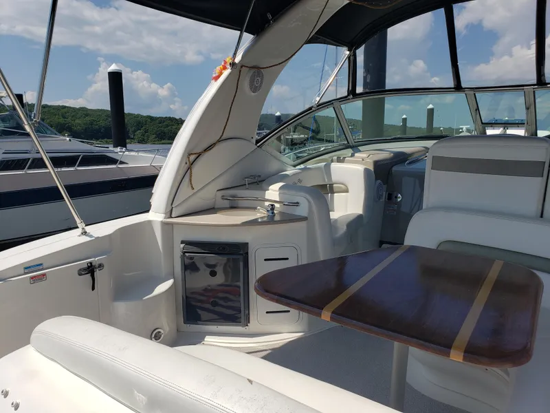 Slide: The Image of 2006 Sea Ray 320 Sundancer yacht interior with seating and table, docked under clear skies. - 18