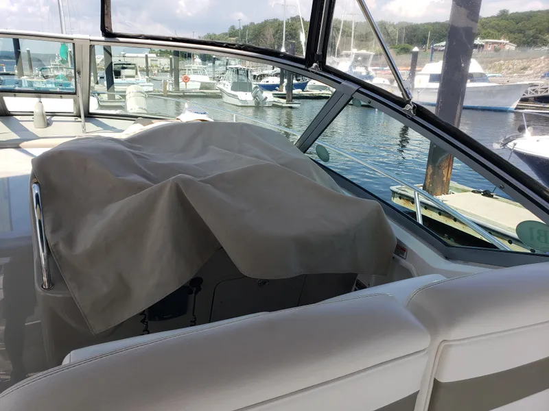 Slide: The Image of 2006 Sea Ray 320 Sundancer boat interior with covered dashboard, docked at marina. - 19