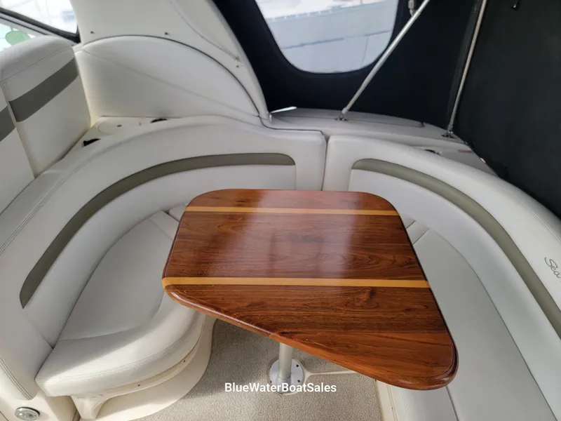 Slide: The Image of 2006 Sea Ray 320 Sundancer interior with curved seating and wooden table. - 29