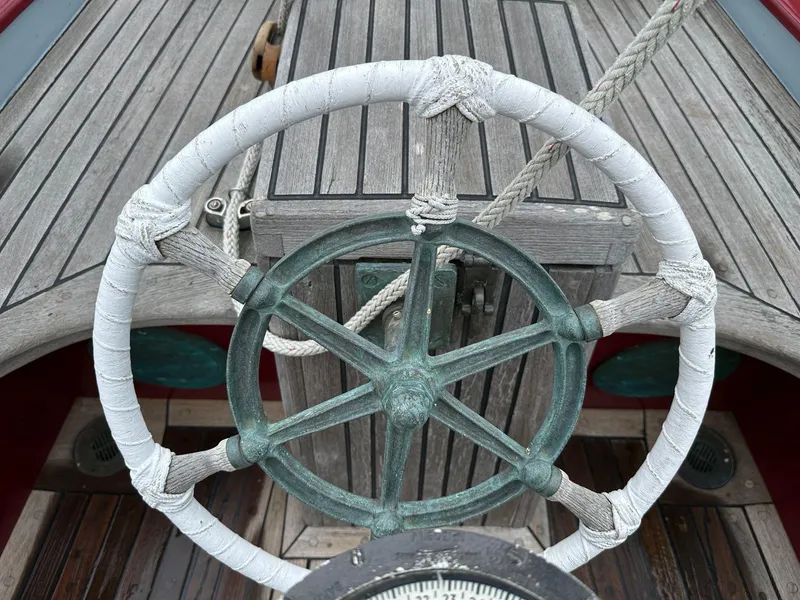 Slide: The Image of Steering wheel of 1947 William Garden 36 Custom Yawl sailboat, featuring classic wooden deck. - 10