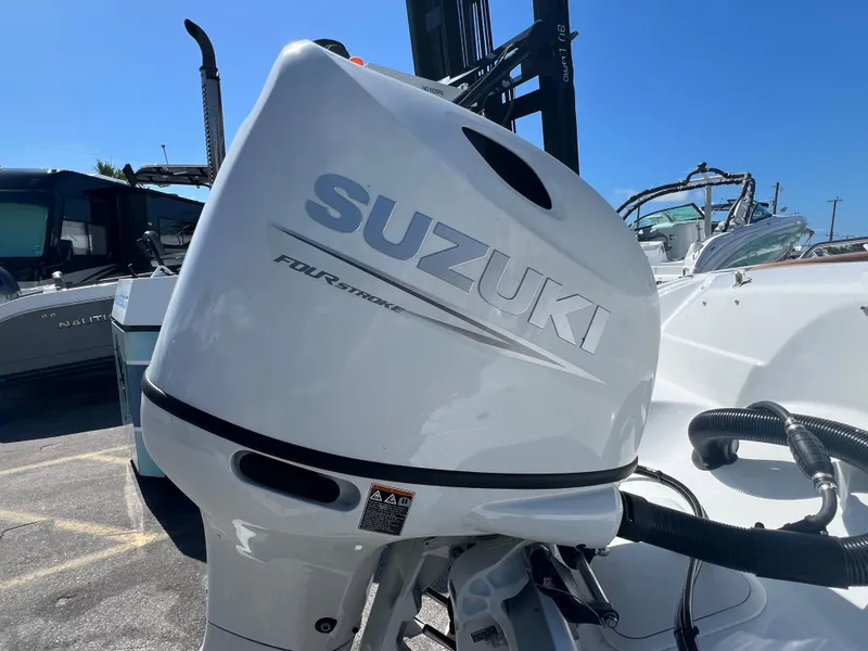 Slide: The Image of 2024 NauticStar 193SC Sport Deck with Suzuki outboard motor in a marina setting. - 11