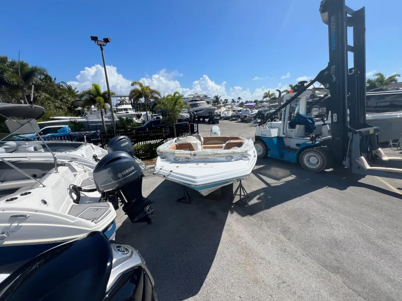 Slide: The Image of 2024 NauticStar 193SC Sport Deck boat in marina, surrounded by other boats and a forklift. - 7