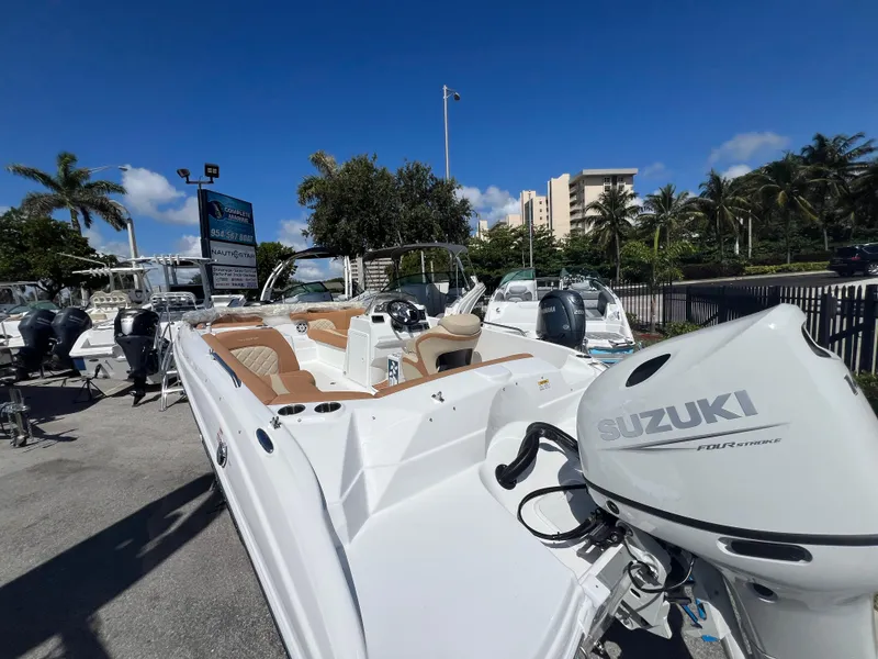 Slide: The Image of 2024 NauticStar 193SC Sport Deck boat with Suzuki outboard motor in a sunny marina. - 8