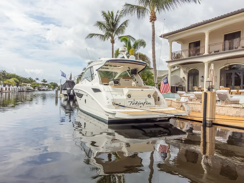 Slide: The Image of 2019 Sea Ray Sundancer 350 Coupe docked by a luxurious waterfront home. - 17
