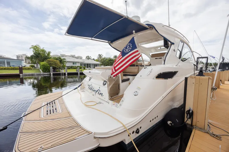 Slide: The Image of 2019 Sea Ray Sundancer 350 Coupe docked with American flag, featuring sleek design and spacious deck. - 21