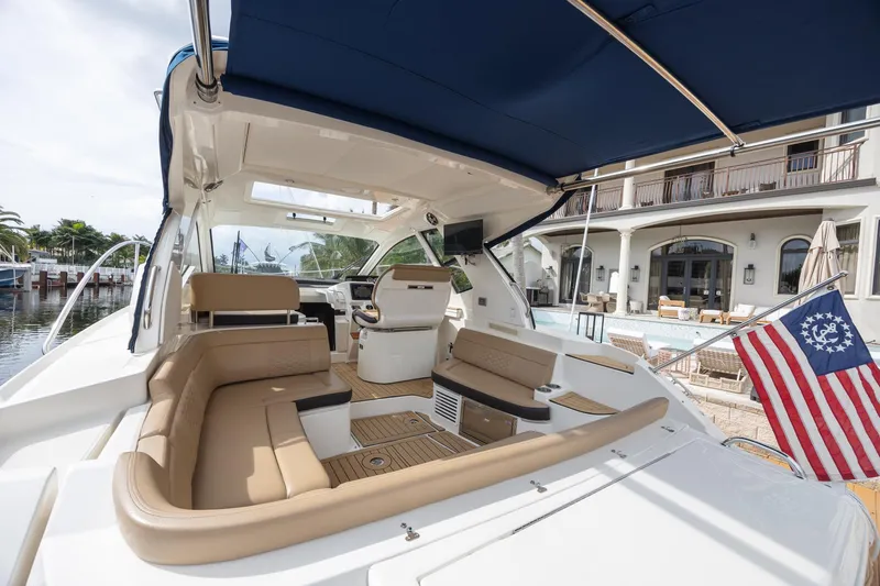 Slide: The Image of 2019 Sea Ray Sundancer 350 Coupe with luxurious seating and canopy, docked near waterfront home. - 23