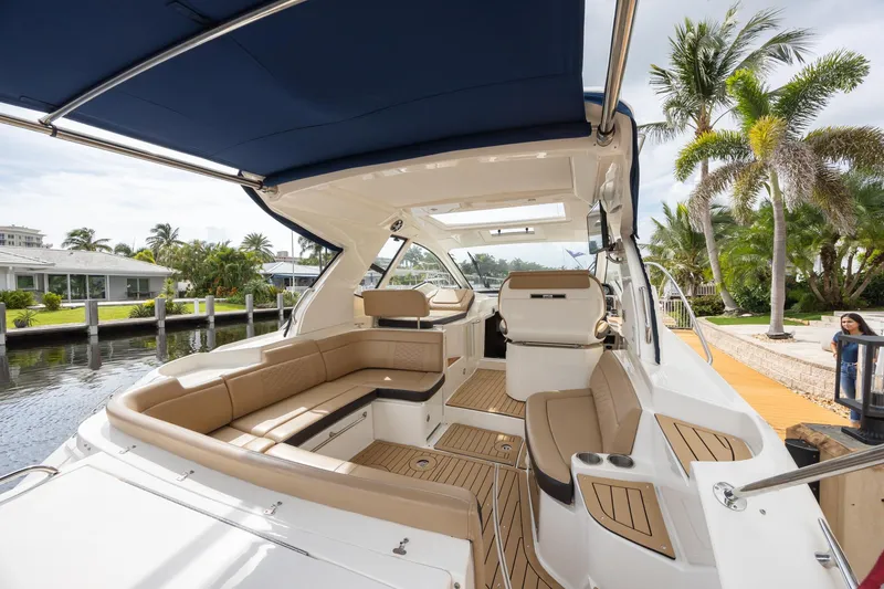 Slide: The Image of 2019 Sea Ray Sundancer 350 Coupe interior with seating, docked near palm trees. - 24