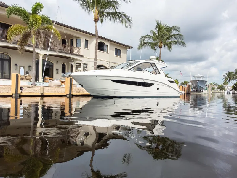 Slide: The Image of 2019 Sea Ray Sundancer 350 Coupe docked by waterfront home, palm trees in background. - 3