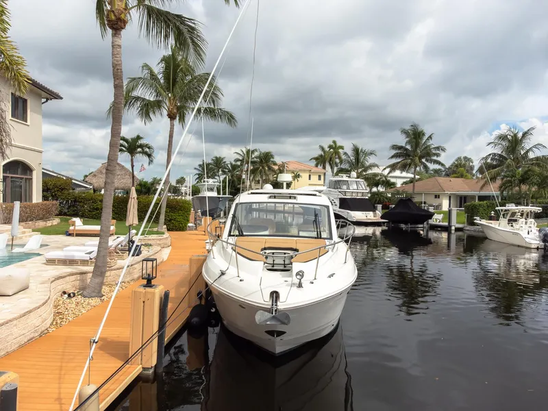 Slide: The Image of 2019 Sea Ray Sundancer 350 Coupe docked in a tropical marina setting. - 6