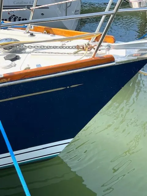 Slide: The Image of 1998 Tartan 4100 sailboat with blue hull and wooden trim docked in water. - 2