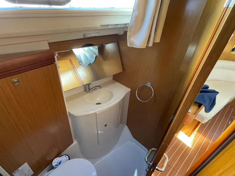 Slide: The Image of 2008 Jeanneau 39i yacht bathroom with sink, mirror, and wooden cabinetry. - 28