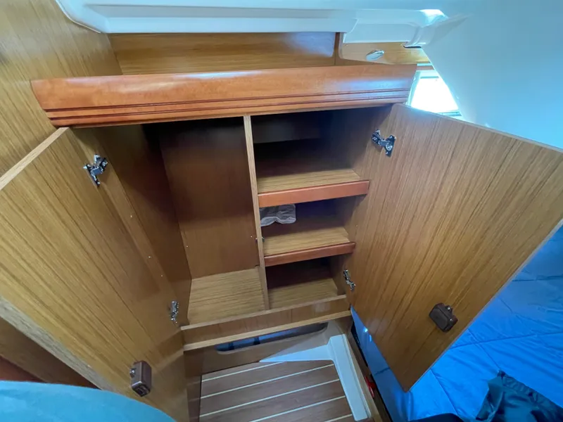 Slide: The Image of 2008 Jeanneau 39i sailboat interior wooden storage cabinet with open doors and shelves. - 31