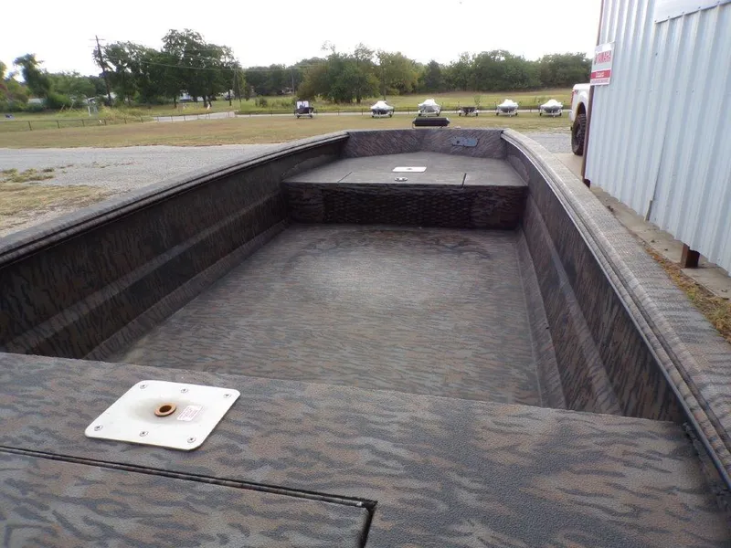 Slide: The Image of 2025 Xpress XTS16 boat interior with camouflage pattern, parked outdoors near a metal building. - 4