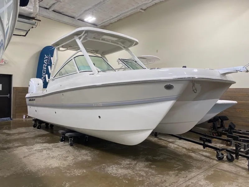 Slide: The Image of 2025 World Cat 230DC boat in showroom, white hull, dual console design. - 1