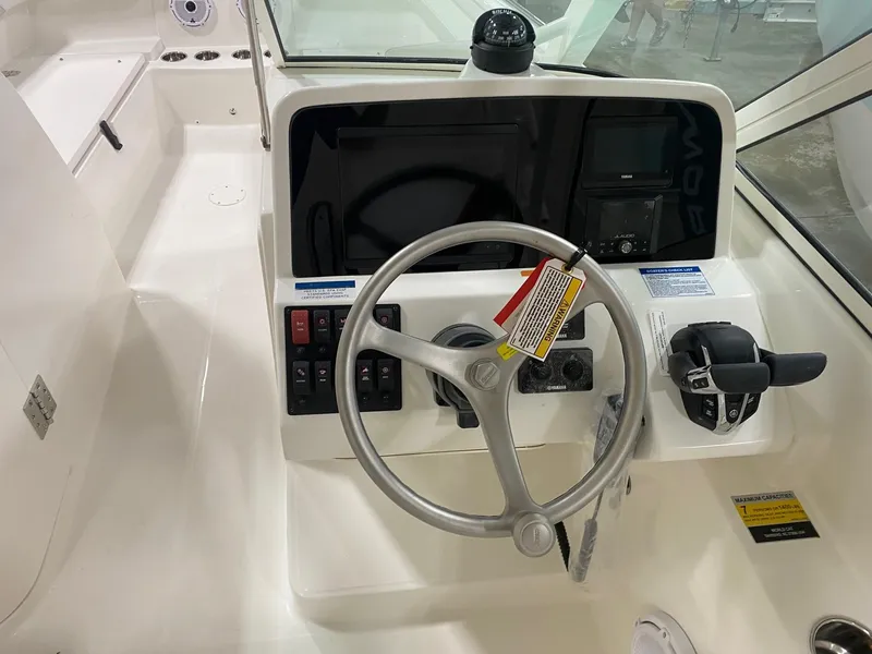 Slide: The Image of 2025 World Cat 230DC boat helm with steering wheel and control panel. - 9