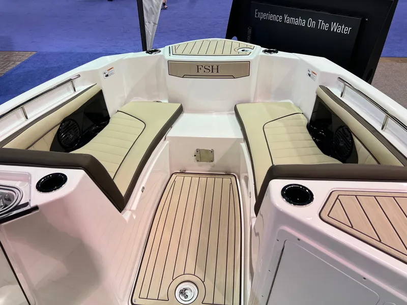Slide: The Image of 2025 Yamaha Boats 255 FSH Sport H interior with beige seating and wood-style flooring. - 8