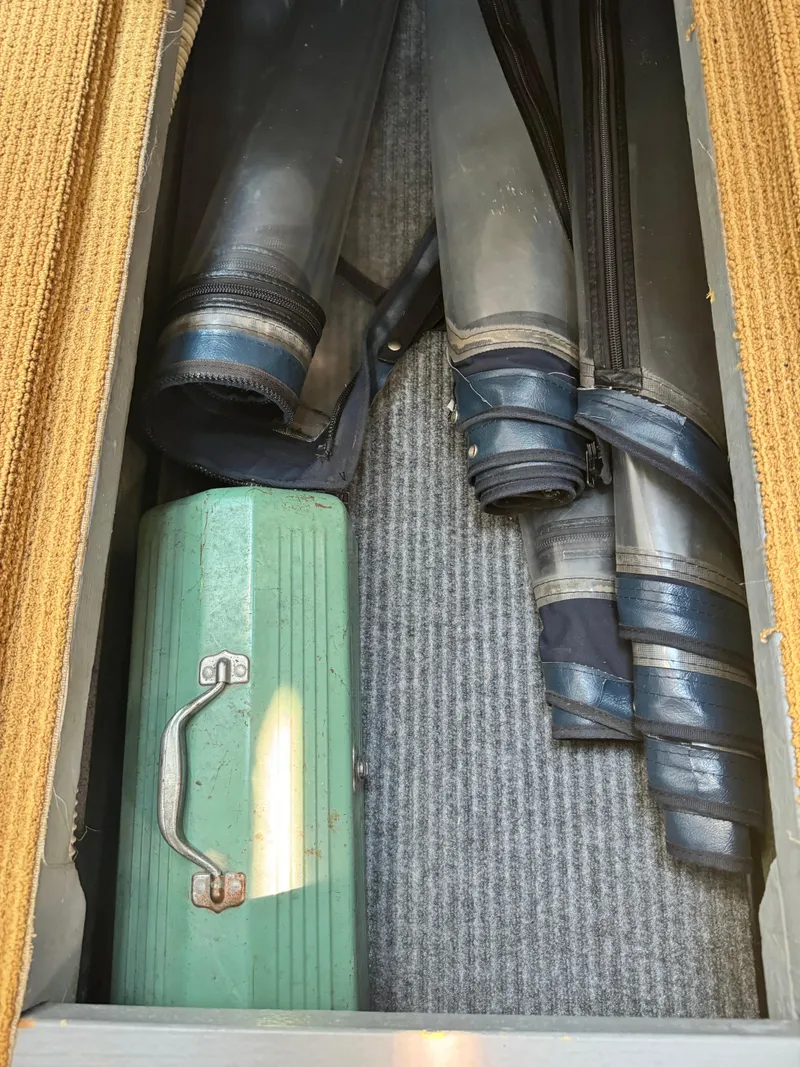Slide: The Image of Storage compartment in a 1995 Sea Ray 370 Express Cruiser with rolled covers and a green toolbox. - 17