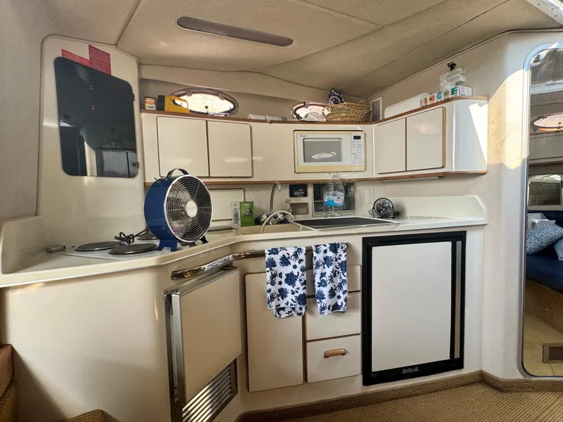 Slide: The Image of 1995 Sea Ray 370 Express Cruiser kitchen with microwave, sink, and compact fridge. - 21