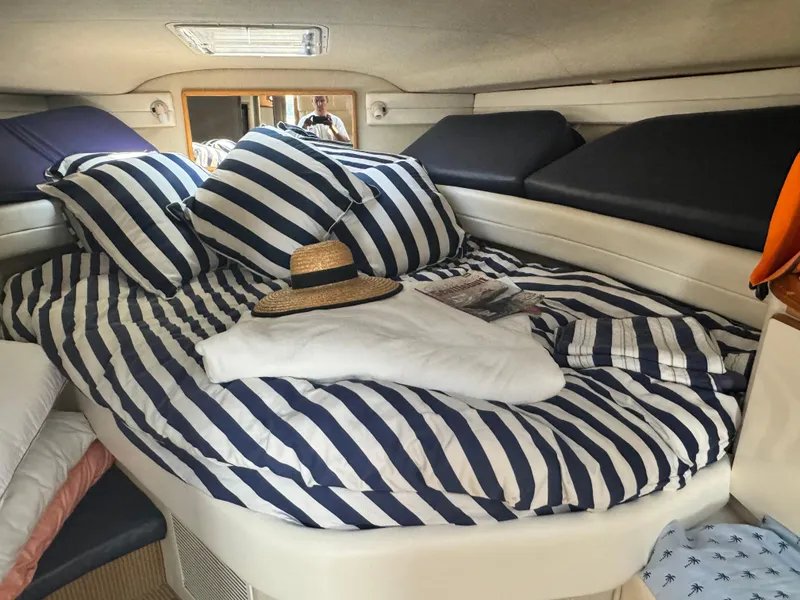 Slide: The Image of Cozy cabin interior of 1995 Sea Ray 370 Express Cruiser with striped bedding and hat. - 34