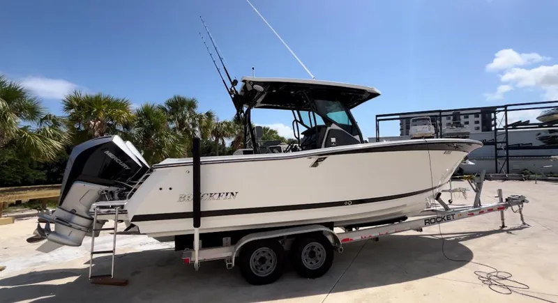 Slide: The Image of 2019 Blackfin 272 CC boat on trailer, parked outdoors under clear sky. - 1