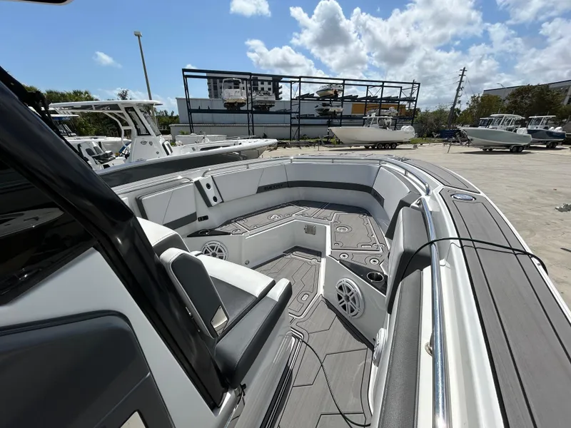 Slide: The Image of 2019 Blackfin 272 CC boat interior with seating and speakers, docked under a sunny sky. - 17