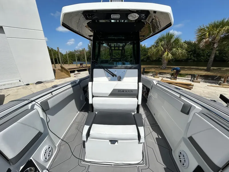 Slide: The Image of 2019 Blackfin 272 CC boat interior with seating and console, surrounded by palm trees. - 19