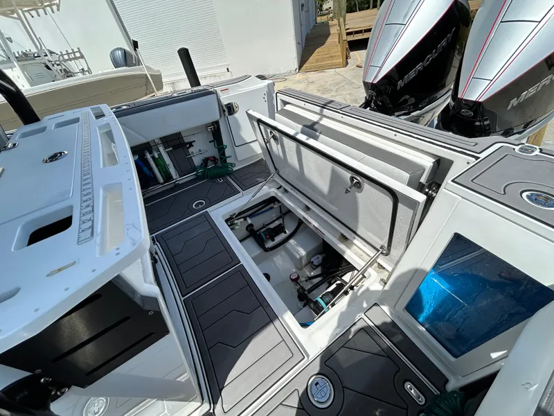Slide: The Image of 2019 Blackfin 272 CC boat interior with open storage compartments and dual Mercury engines. - 24