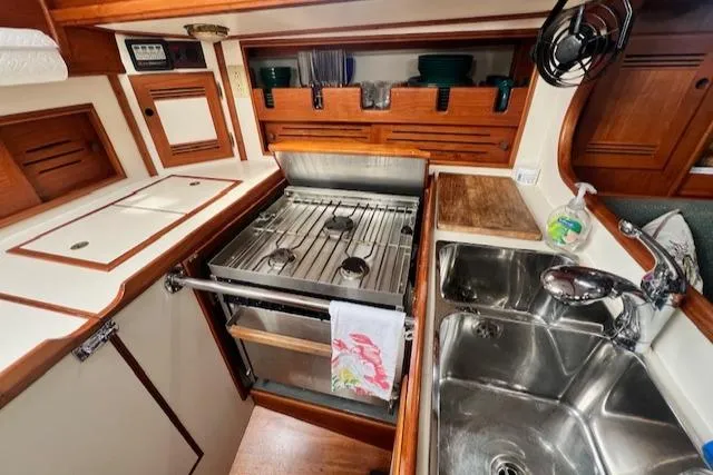 Slide: The Image of 1999 Robinhood Cutter yacht kitchen with stove, sink, and wooden cabinetry. - 11
