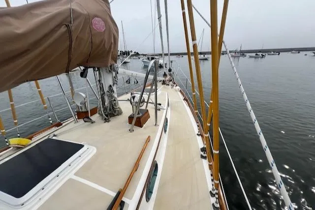 Slide: The Image of Sailboat deck view, Robinhood Cutter 1999, moored in calm waters with distant boats. - 24