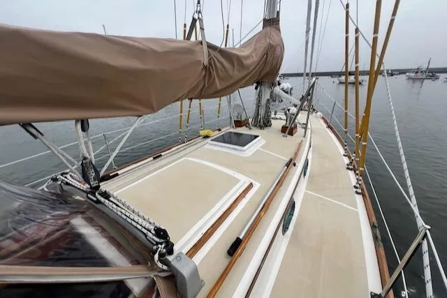 Slide: The Image of Sailboat deck of 1999 Robinhood Cutter, featuring tan sail cover and rigging, docked in calm waters. - 25