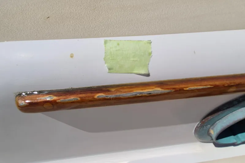 Slide: The Image of Wooden handrail on a 1999 Robinhood Cutter boat, with visible wear and green tape. - 58