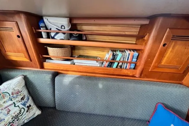 Slide: The Image of Cozy 1999 Robinhood Cutter interior with wooden shelves, books, and cushions. - 6