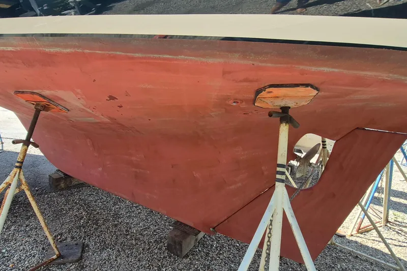 Slide: The Image of 1999 Robinhood Cutter boat hull on stands, showing red paint and structural supports. - 61