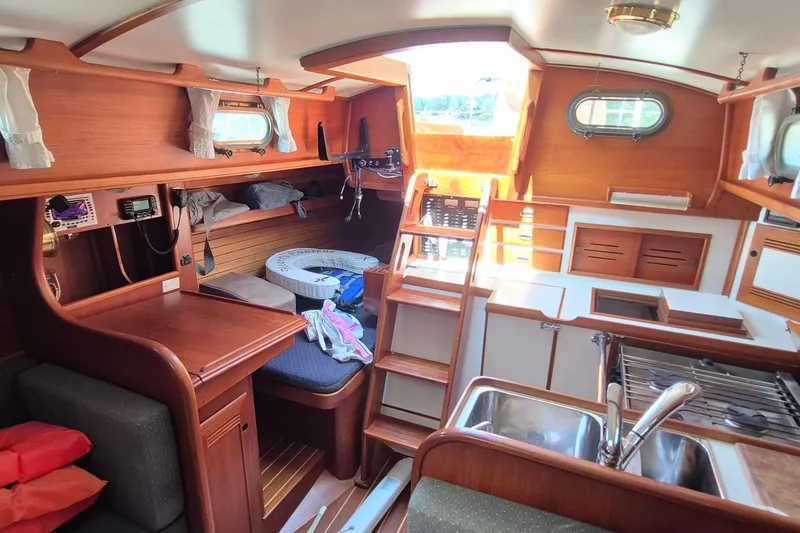 Slide: The Image of Interior of 1999 Robinhood Cutter sailboat with wooden cabinetry and compact kitchen area. - 10