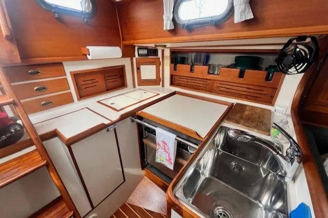 Slide: The Image of Compact kitchen area in a 1999 Robinhood Cutter sailboat with wooden cabinetry and stainless steel sink. - 12