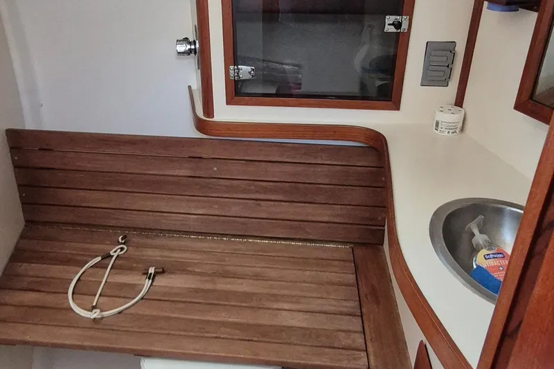 Slide: The Image of 1999 Robinhood Cutter boat interior with wooden bench, sink, and storage. - 17