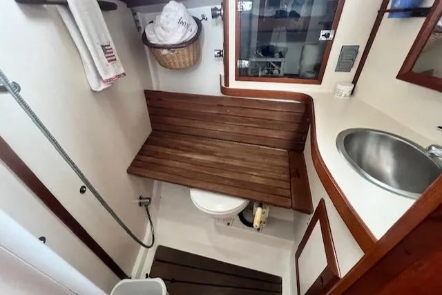 Slide: The Image of 1999 Robinhood Cutter boat bathroom with wooden bench, sink, and shower area. - 18