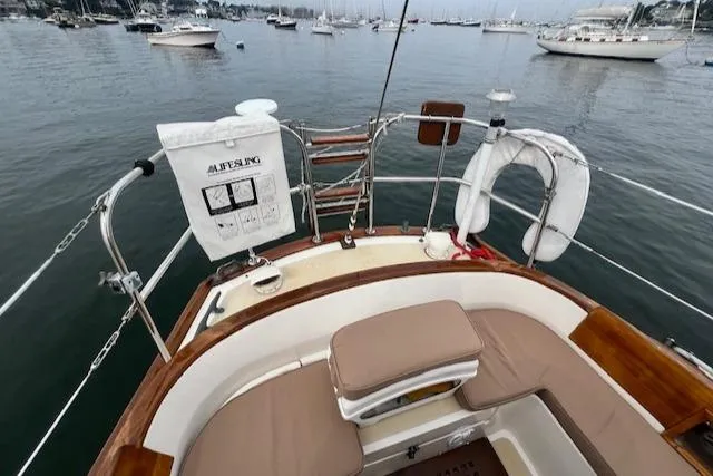 Slide: The Image of Sailboat deck view with seating, life preserver, and scenic harbor background. Robinhood Cutter 1999. - 31