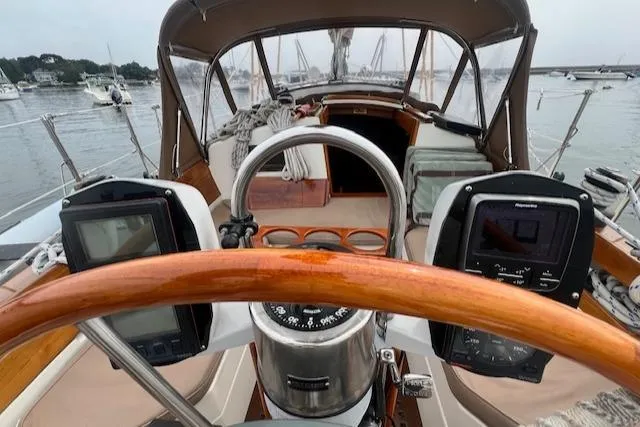 Slide: The Image of Cockpit view of a 1999 Robinhood Cutter sailboat with navigation instruments and wooden steering wheel. - 34