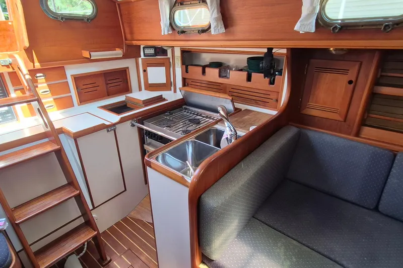 Slide: The Image of Cozy 1999 Robinhood Cutter yacht interior with wooden cabinetry and compact kitchen area. - 7