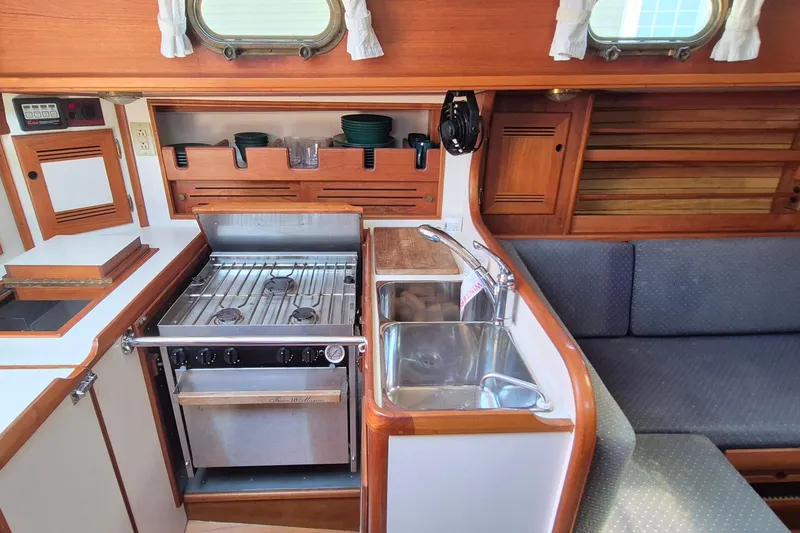 Slide: The Image of Compact kitchen in a 1999 Robinhood Cutter boat with stove, sink, and seating area. - 8