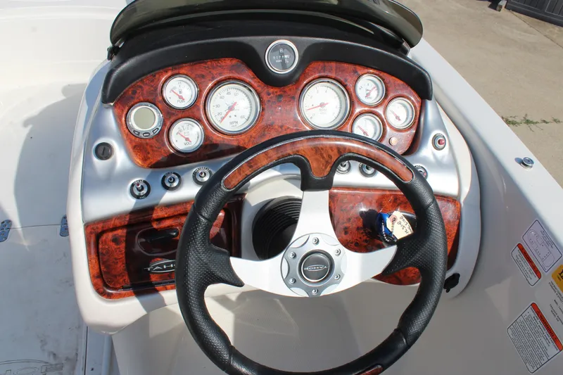 Slide: The Image of 2015 Tahoe 215 I/O boat dashboard with wood grain finish and steering wheel. - 16