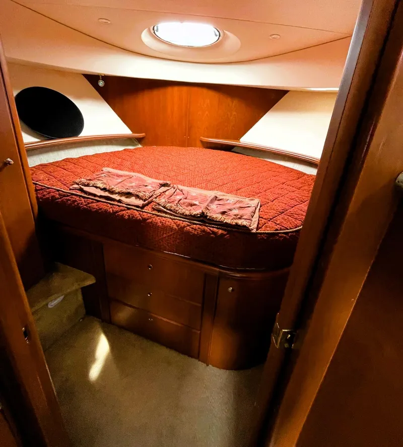 Slide: The Image of 2006 Silverton 39 Motor Yacht bedroom with red bedding and wooden interior. - 46