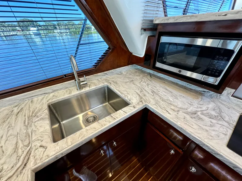 Slide: The Image of Navigator Pilothouse 1998 yacht kitchen with marble countertop, stainless steel sink, and microwave. - 25