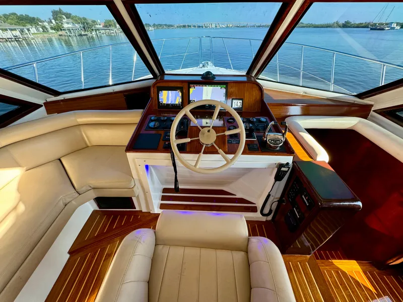 Slide: The Image of 1998 Navigator Pilothouse yacht interior with leather seating and wooden accents, overlooking serene waters. - 33